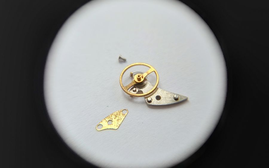 Underside of the balance wheel showing the double roller, impulse jewel, staff and pivot