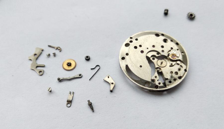 The disassembled keyless works components laid out beside the main plate