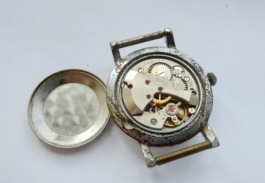 Watch case opened with the domed back removed, exposing the Zarya 2008 movement with its raised gear-train bridge