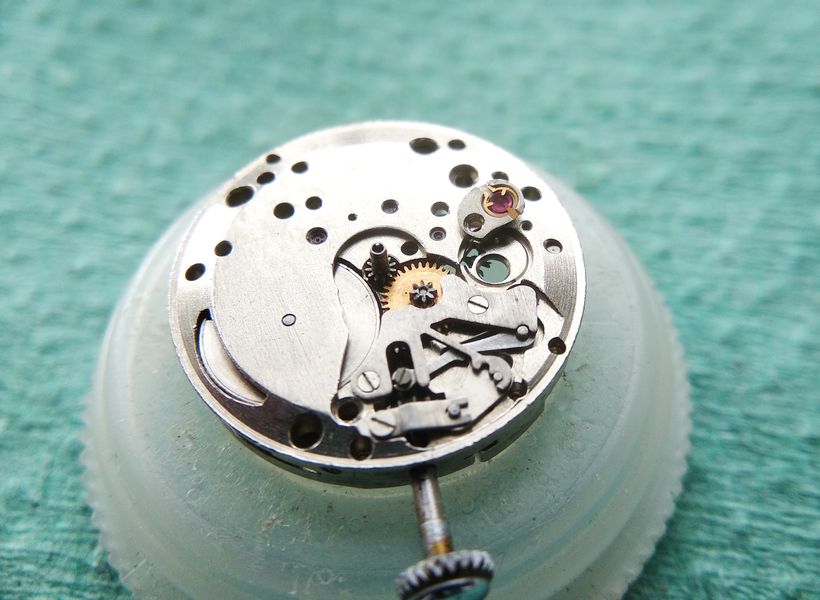 The cap-jewel retaining spring of the bushing being swung open while remaining captive in its frame