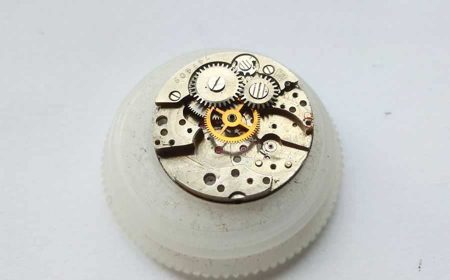 The winding wheels of the mainspring motor being removed from the plate