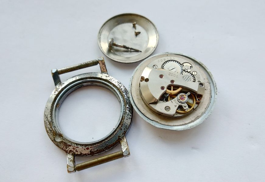 Bare movement removed from the case and resting dial-up on the bench