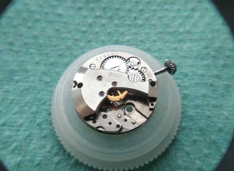 A Kinder-egg plastic capsule used as a dust cover over the partly assembled oiled movement