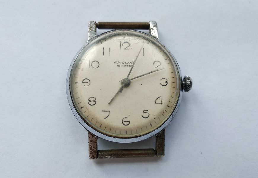 Front of a worn Yunost wristwatch with a silvered dial reading Yunost and 15 jewels, in a battered chrome case