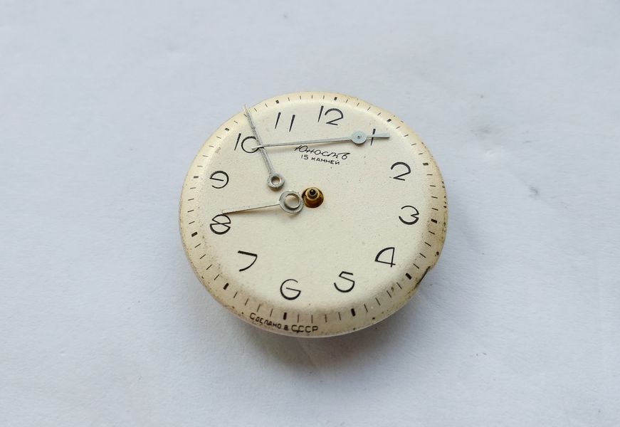 The watch hands freed and resting on the protective film over the dial
