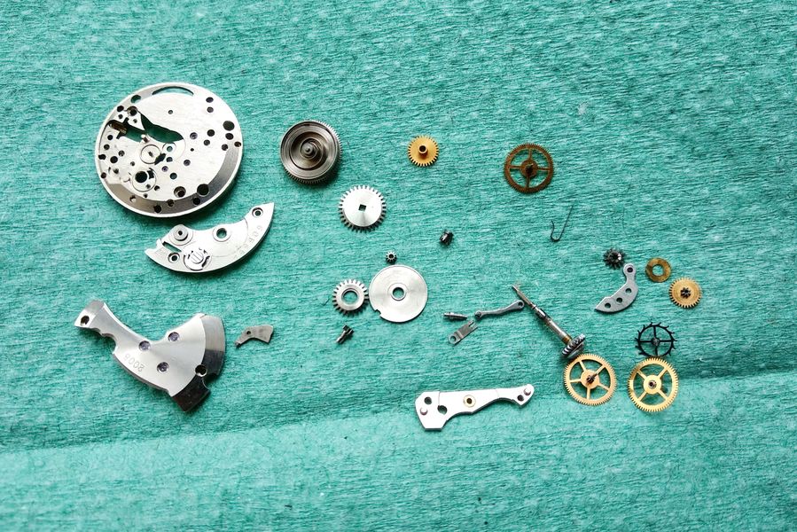 All cleaned movement parts arranged on a green blotter ready for reassembly