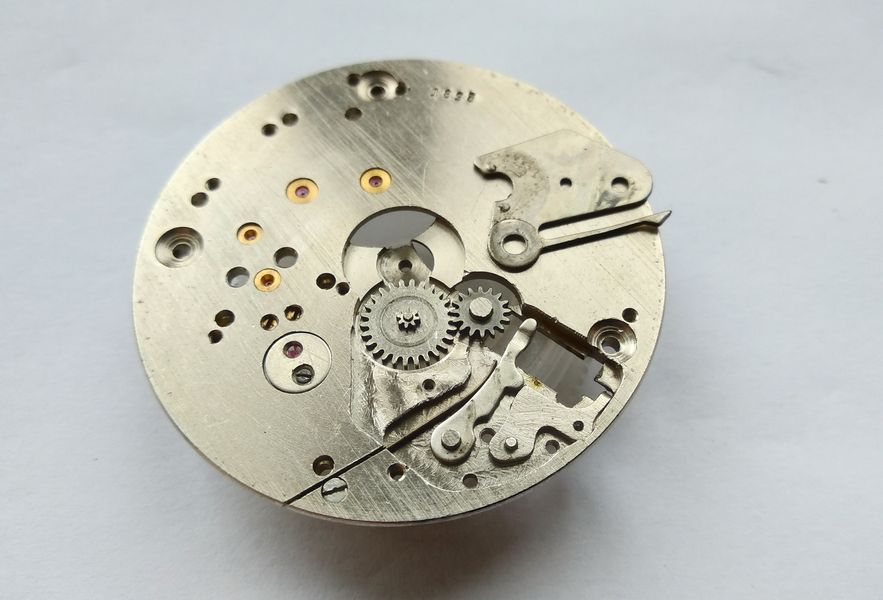 Keyless works exposed: stamped intermediate and setting levers, minute and setting wheels, and a screwed flat setting-lever spring